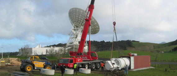 A crane lifting a satellite dish into position